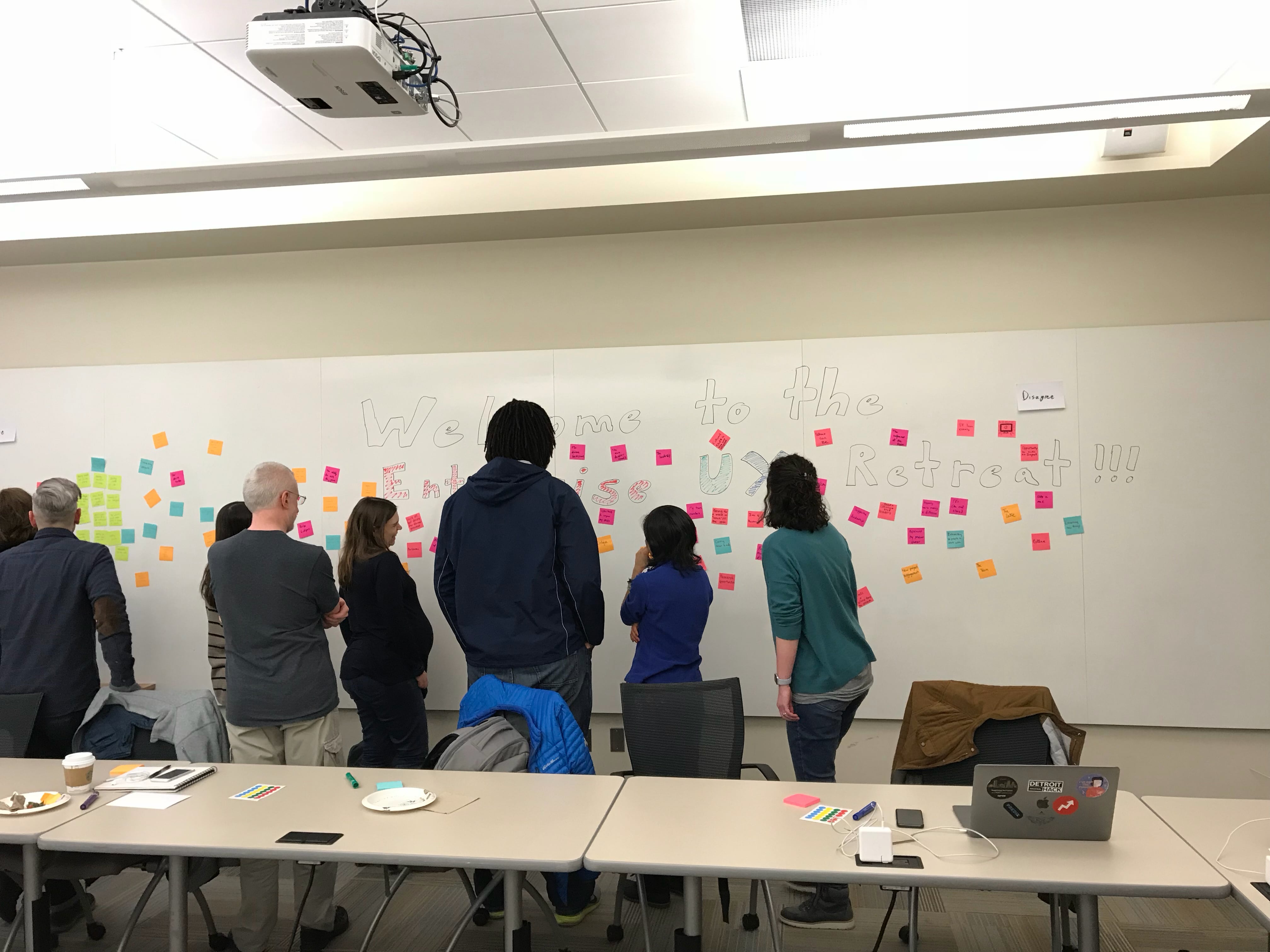 A team-building UX retreat workshop at GE — the team gathered at a sticky-note wall